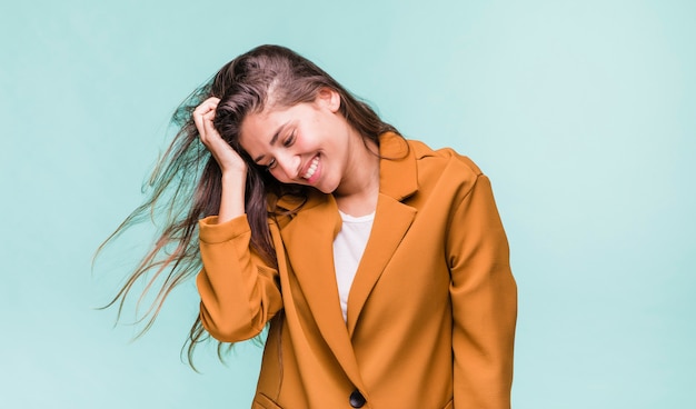 Ragazza castana sorridente che posa con il cappotto