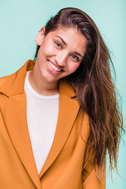 Ragazza castana sorridente che posa con il cappotto