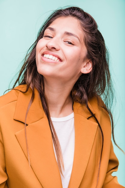 Ragazza castana sorridente che posa con il cappotto