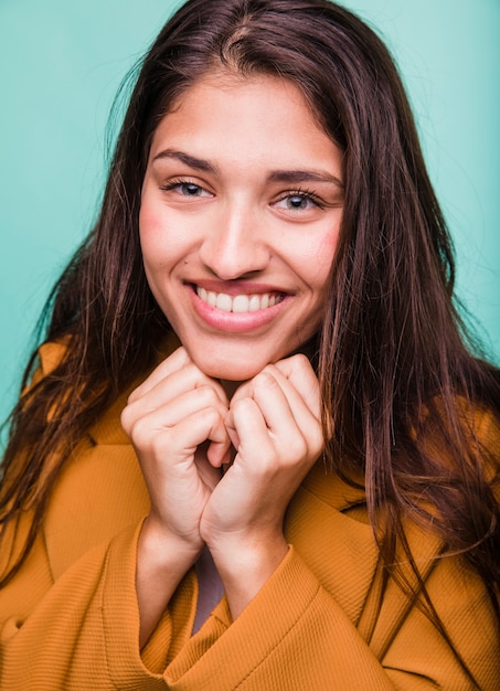 Ragazza castana sorridente che posa con il cappotto