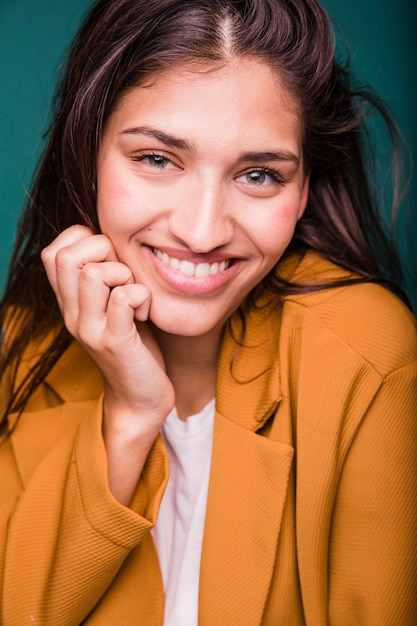 Ragazza castana sorridente che posa con il cappotto