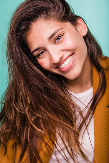 Ragazza castana sorridente che posa con il cappotto