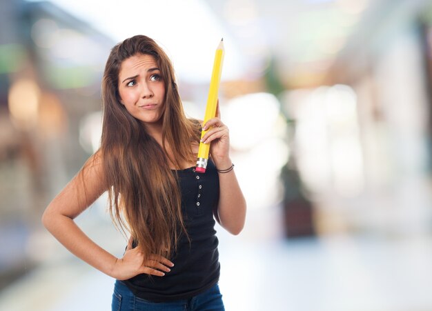 Ragazza casuale che tiene una grande matita