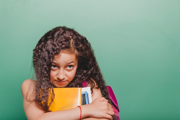 Ragazza che abbraccia libri a lavagna