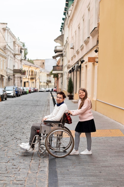 Ragazza che aiuta un disabile che viaggia in città