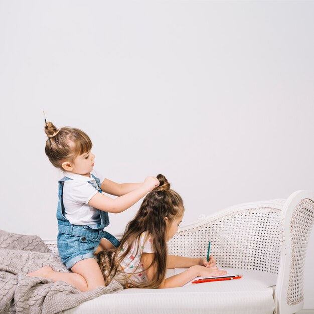 Ragazza che attinge carta con la matita mentre un&#39;altra ragazza che mette i suoi capelli