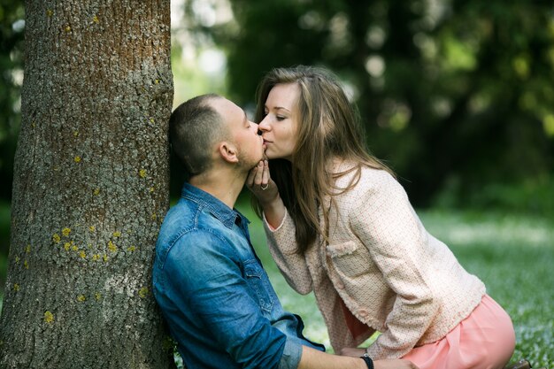 Ragazza che bacia ragazza che si siede contro l&#39;albero