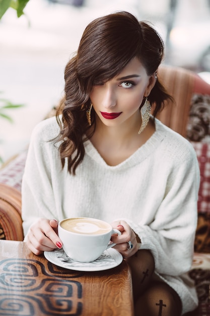 Ragazza che beve caffè in un caffè alla moda