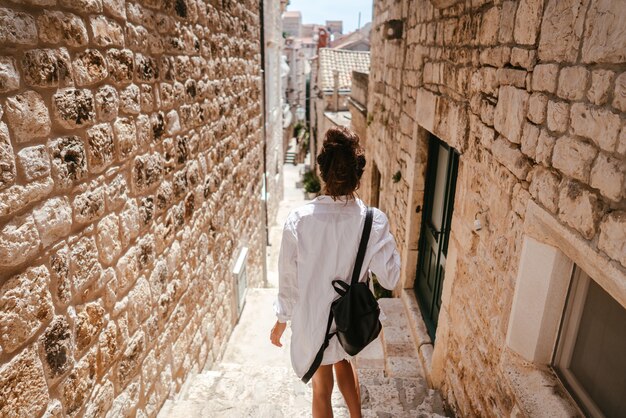 Ragazza che cammina attraverso antiche stradine in una bella giornata estiva