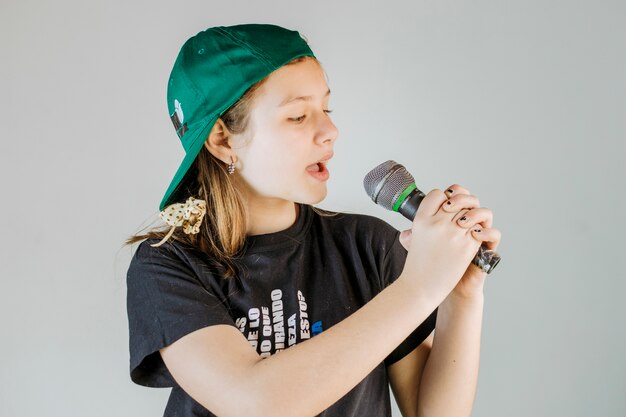 Ragazza che canta la canzone con microfono su sfondo grigio