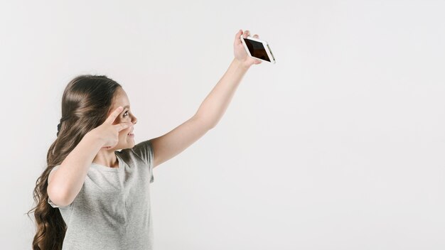 Ragazza che cattura selfie divertente sul cellulare in studio