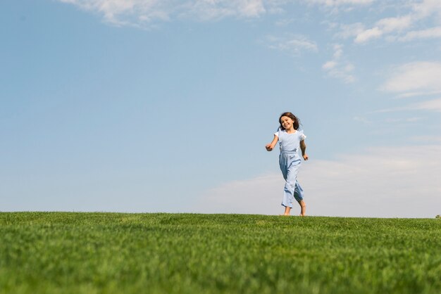 Ragazza che corre a piedi nudi sull'erba