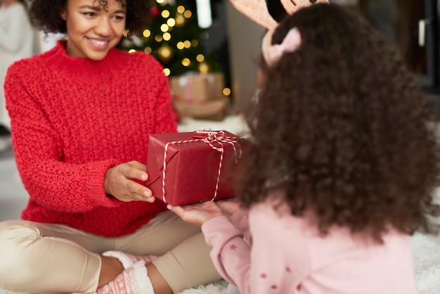 Ragazza che dà a mamma il regalo di Natale