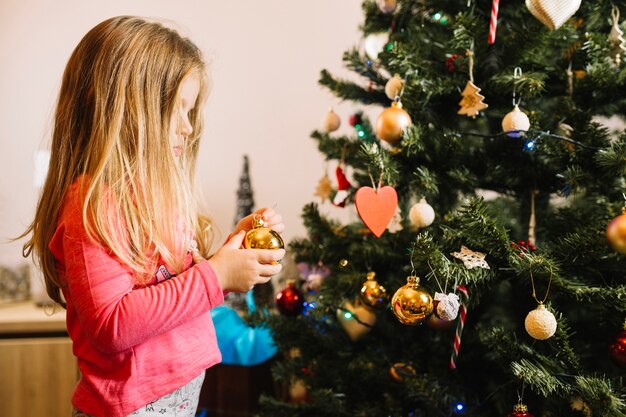 Ragazza che decorano albero di natale