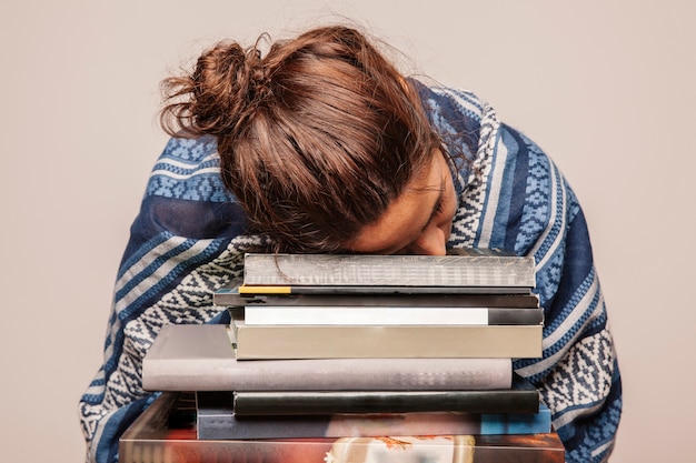 Ragazza che dorme sulla pila di libri