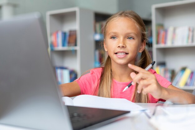 Ragazza che fa i compiti mentre guarda il laptop