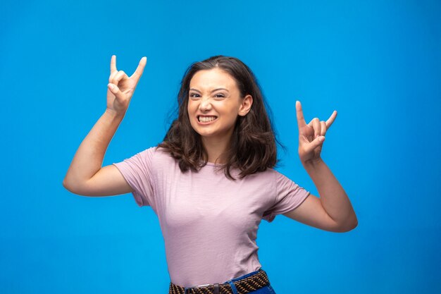 Ragazza che fa il simbolo della pace con le dita e piuttosto sorridente.