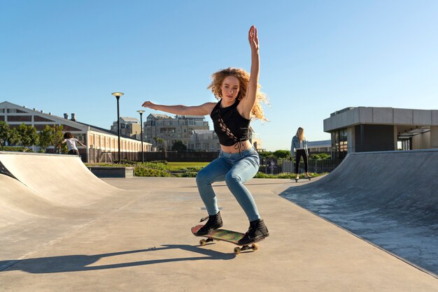 Ragazza che fa trucchi sul colpo pieno di skateboard