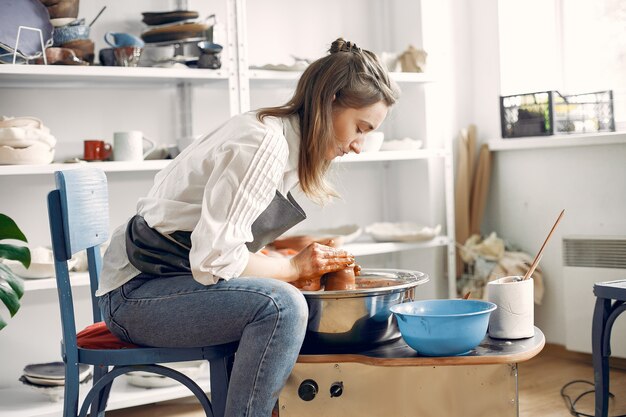 Ragazza che fa un labirinto da un'argilla sulla macchina di una ceramica