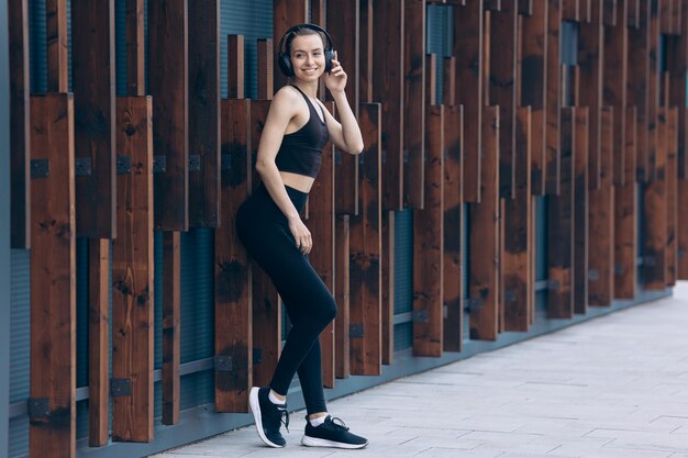 Ragazza che ha una pausa dall'allenamento ascoltando musica negli auricolari