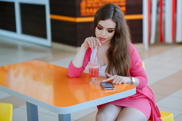 Ragazza che ha una soda mentre guardando il suo telefono