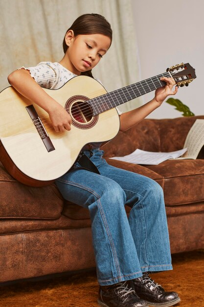 Ragazza che impara a suonare la chitarra a casa