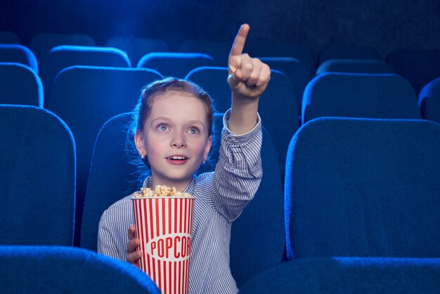 Ragazza che indica con il dito allo schermo nel cinema.