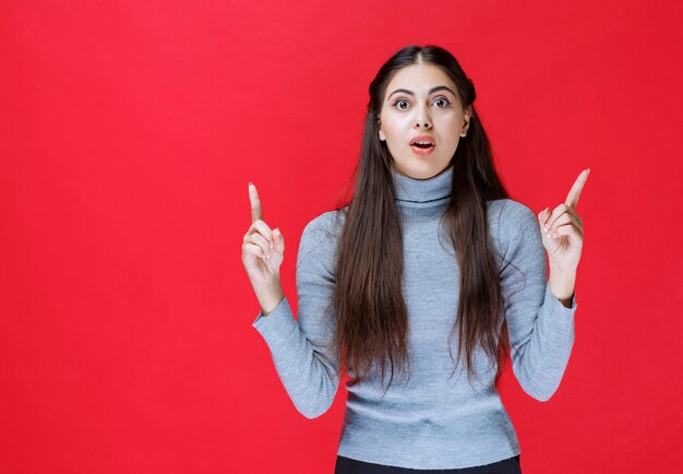 Ragazza che indica verso l'alto e mostra qualcosa sopra.