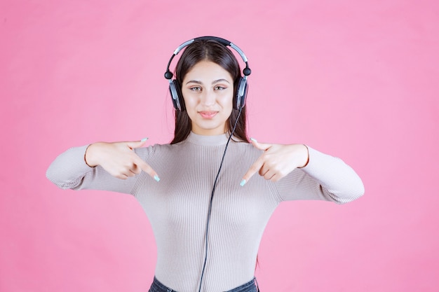 Ragazza che indossa le cuffie e indica da qualche parte