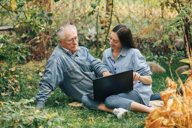 Ragazza che insegna a suo nonno come usare un computer portatile