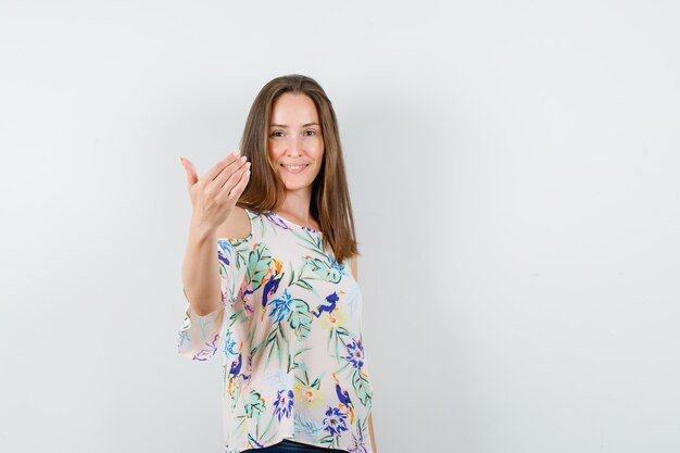 Ragazza che invita a venire in camicia, jeans e aspetto amichevole, vista frontale.