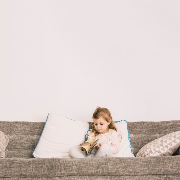 Ragazza che legge la rivista sul divano