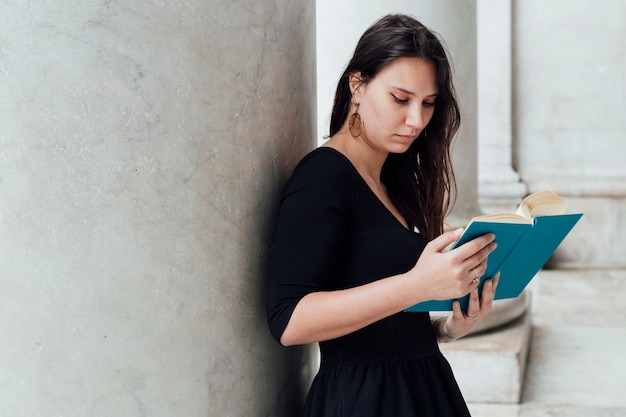 Ragazza che legge un libro in strada