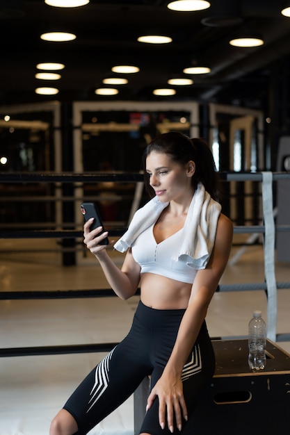 Ragazza che manda un sms mentre fa una pausa in una palestra. Legge un messaggio