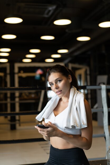 Ragazza che manda un sms mentre fa una pausa in una palestra. Legge un messaggio