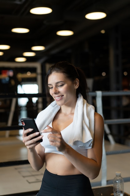 Ragazza che manda un sms mentre fa una pausa in una palestra. Legge un messaggio