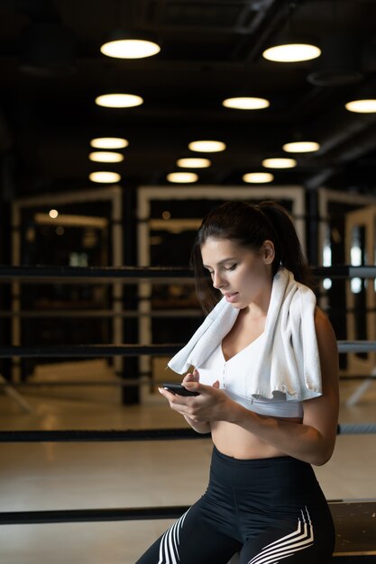 Ragazza che manda un sms mentre fa una pausa in una palestra. Legge un messaggio