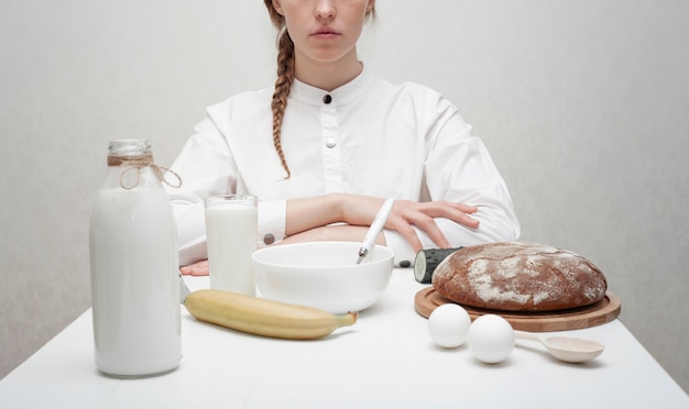 Ragazza che mangia prima colazione su una tabella bianca