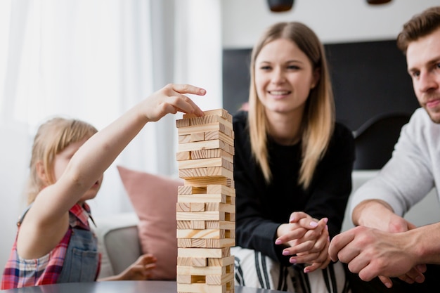 Ragazza che mette il blocco sulla torre vicino ai genitori