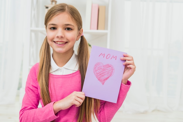 Ragazza che mostra biglietto di auguri con iscrizione mamma