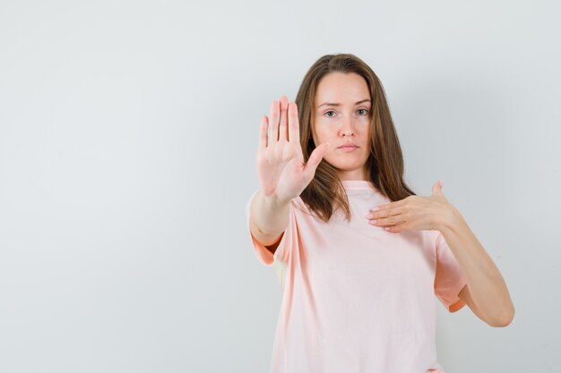 Ragazza che mostra il gesto di rifiuto in maglietta rosa e che sembra rigorosa