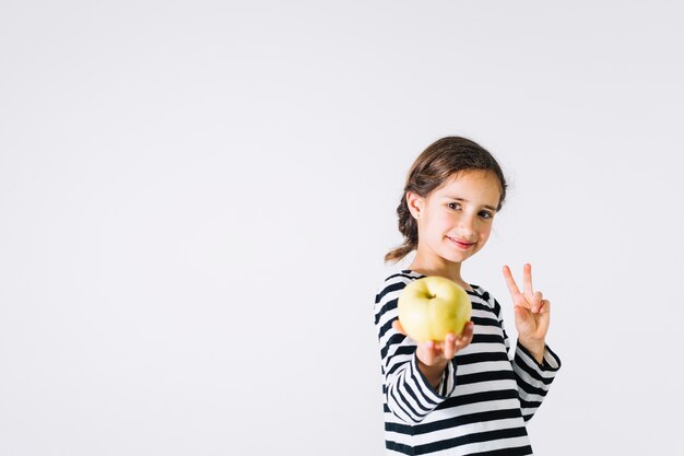 Ragazza che offre mela e pace gesticolare