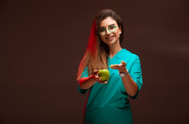 Ragazza che offre una mela verde in mano.