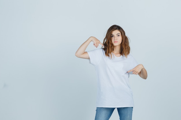 Ragazza che osserva da parte in t-shirt, jeans e affascinante, vista frontale.