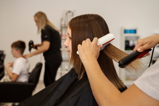 Ragazza che ottiene capelli acconciati alla vista laterale del salone