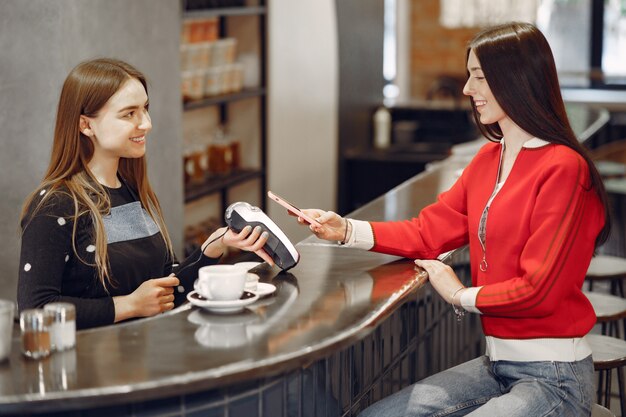 Ragazza che paga per il suo latte con uno smartphone con la tecnologia PAY PASS senza contatto