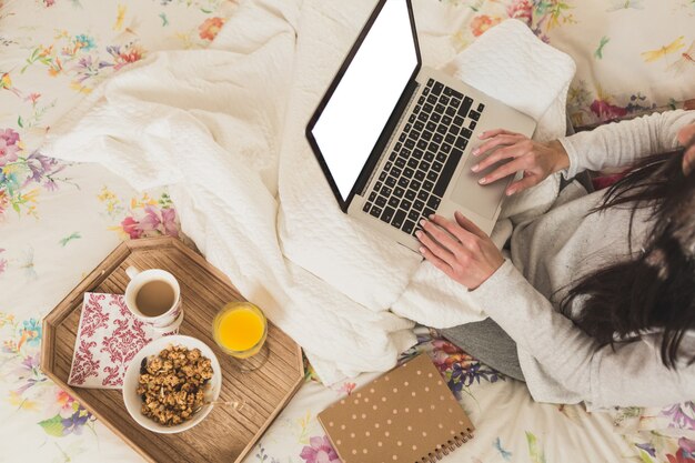 Ragazza che per mezzo del suo computer portatile sul letto