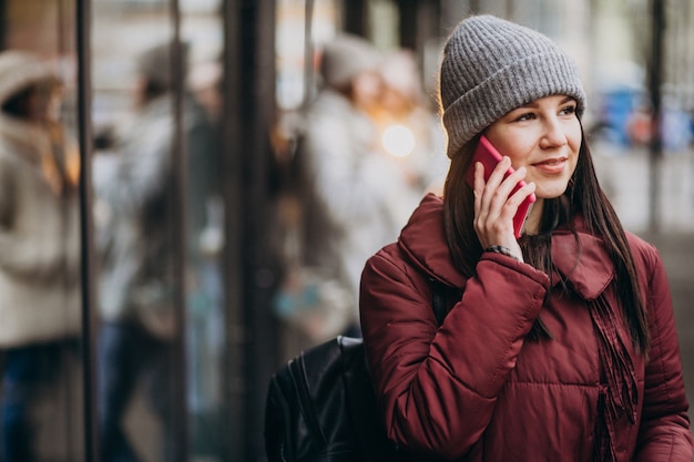 Ragazza che per mezzo del telefono fuori della strada e incontrando gli amici