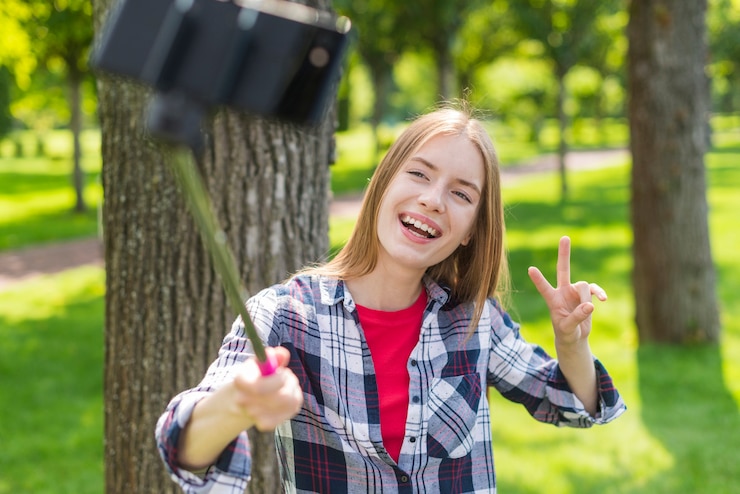 Foto gratuito ragazza che per mezzo di un bastone del selfie per una foto