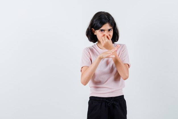 Ragazza che pizzica il naso a causa del cattivo odore in maglietta rosa e pantaloni neri e sembra tormentata